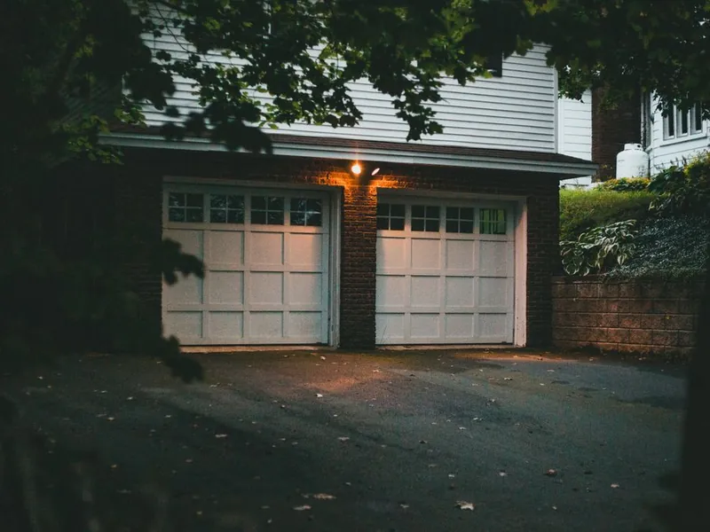 Carriage-style garage doors lit by porch lights at night for emergency service